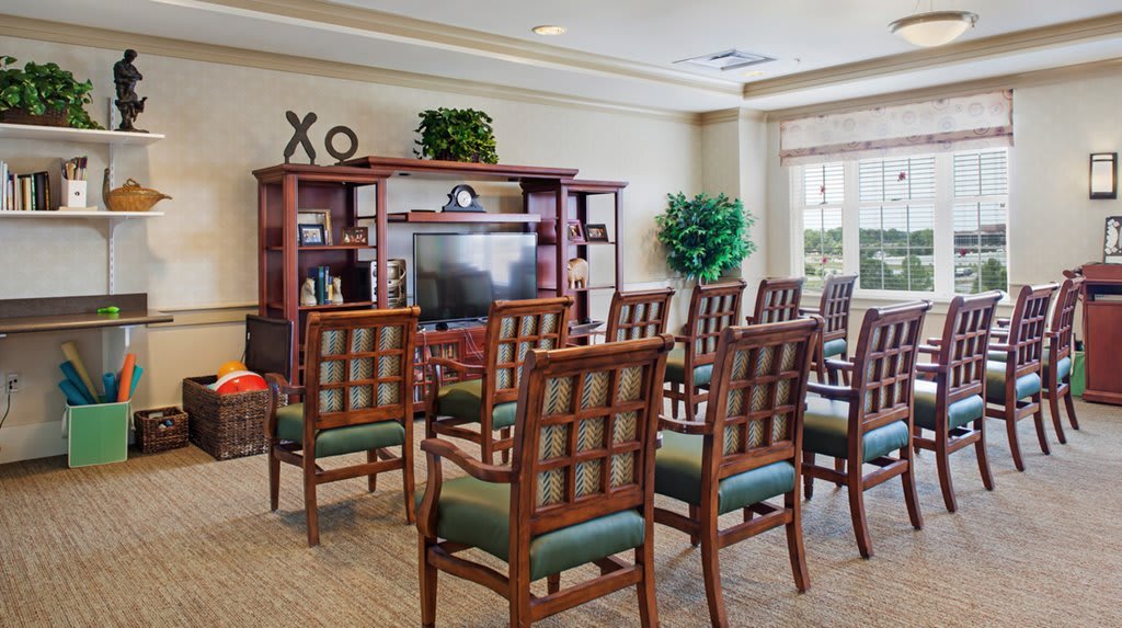 A well-arranged conference room with wooden chairs facing a television.