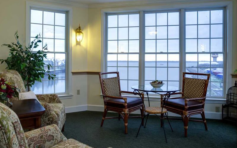 A cozy living room with a lake view, featuring a small table and chairs by large windows.