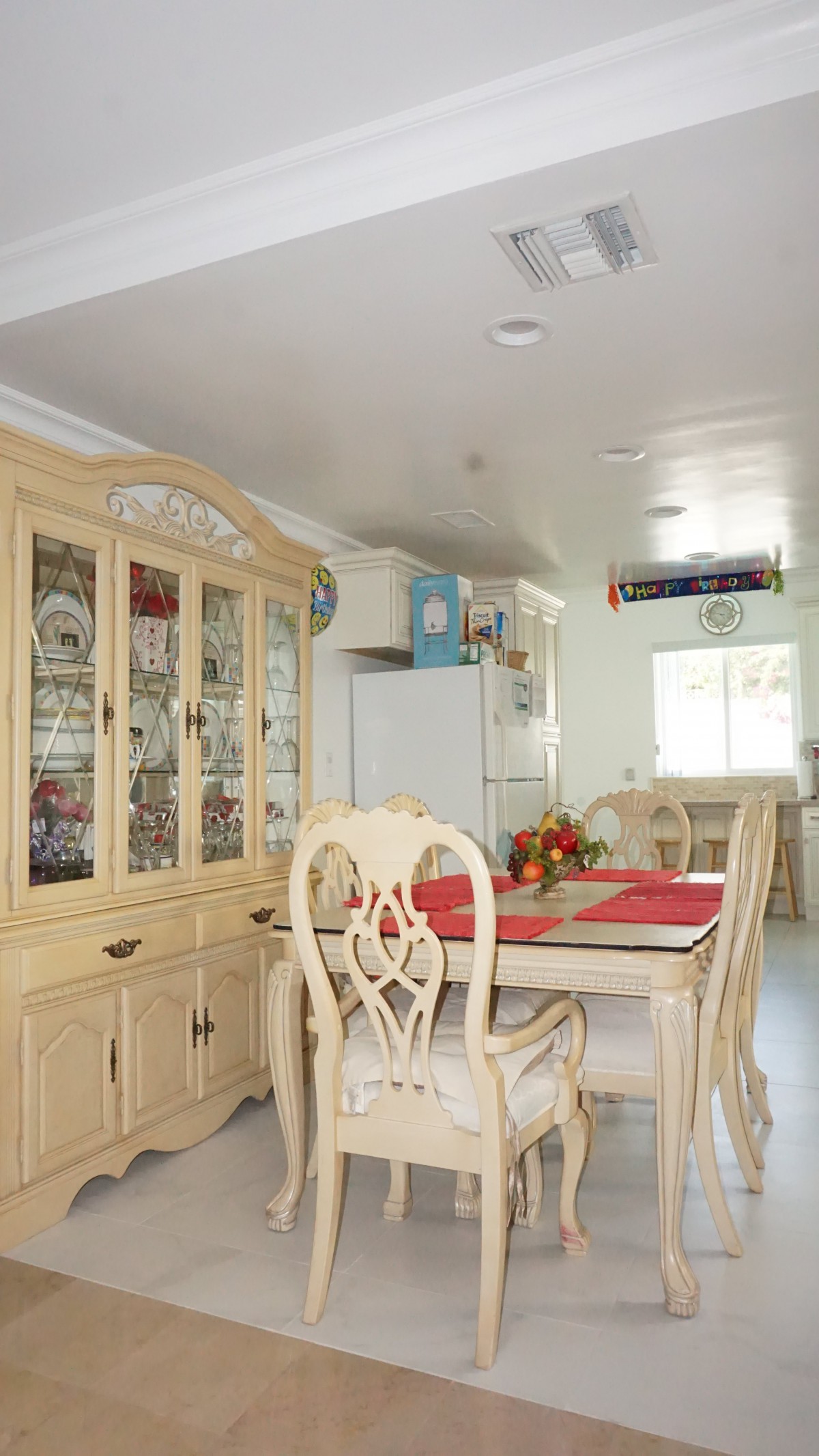 A bright dining area featuring a decorative cabinet and a wooden dining set with red placemats.