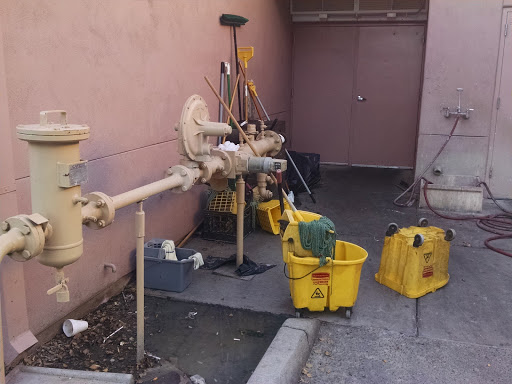 Cleaning supplies and utility pipes stored in a commercial space.