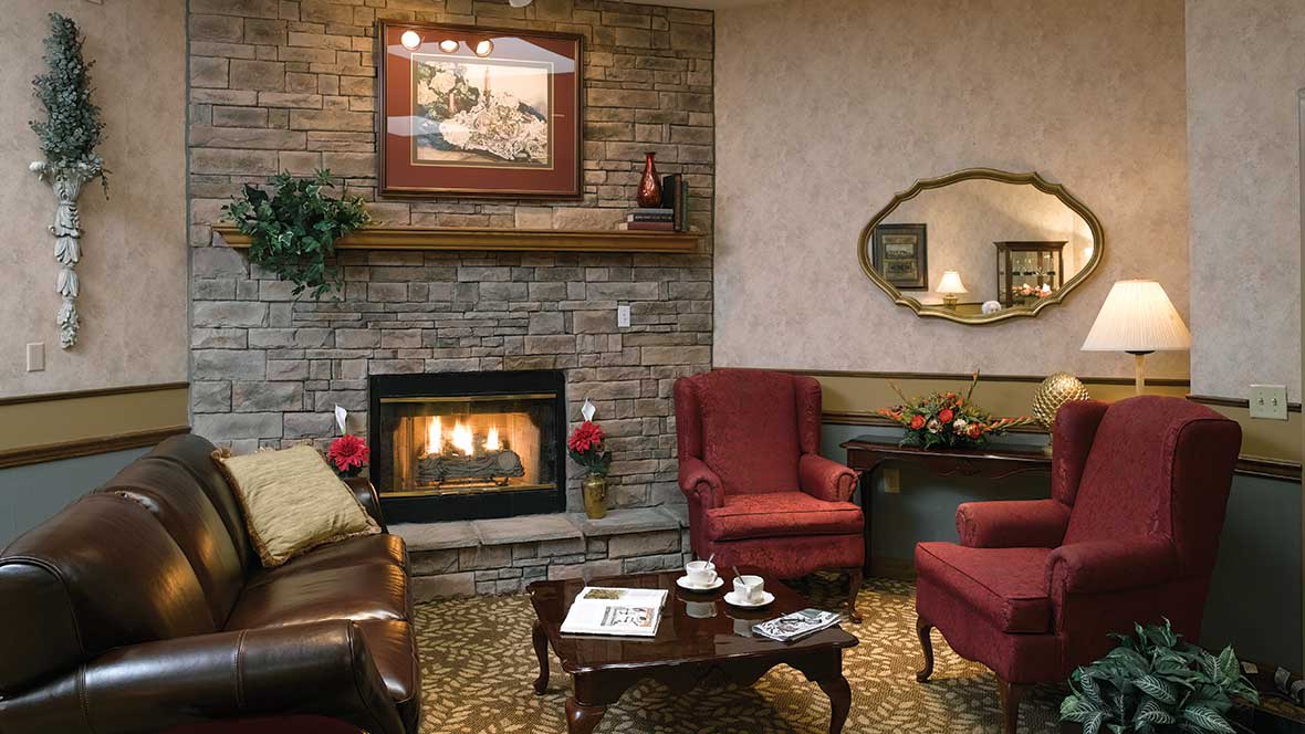 A cozy living room with a fireplace, traditional decor, armchairs, and a coffee table.