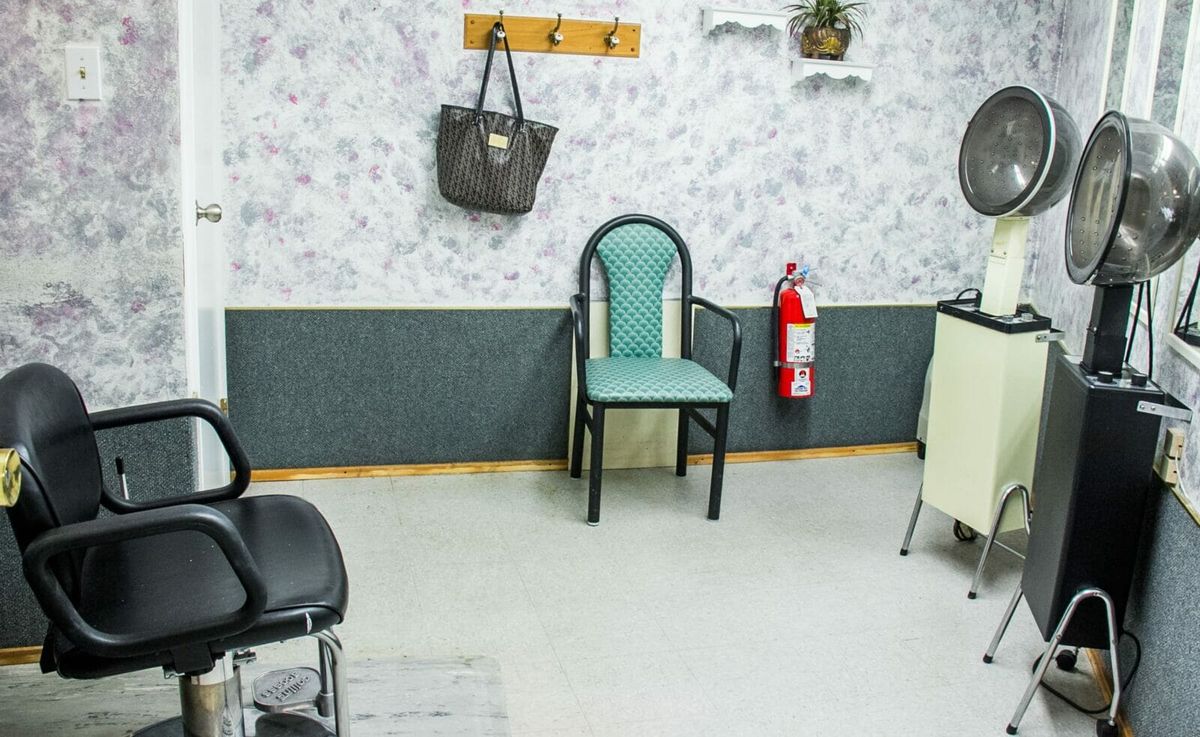 A small waiting area with chairs, a fire extinguisher, and a purse hanging on coat hooks.