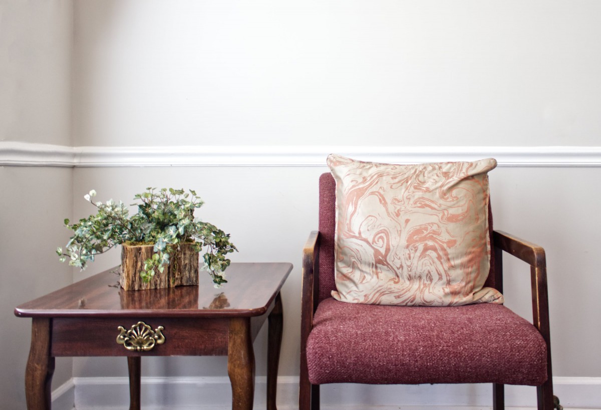 A cozy living space with a cushioned chair and a small side table adorned with plants.