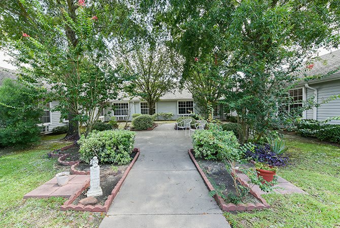 A residential house with a landscaped front yard and walkway surrounded by trees.