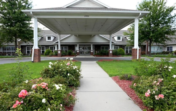 A well-maintained building entrance with a covered walkway and landscaped garden.
