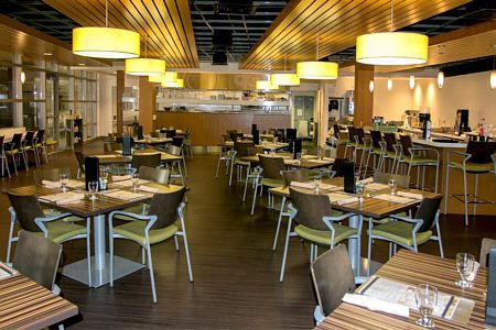 A modern restaurant interior with neatly arranged tables and chairs, featuring stylish lighting.