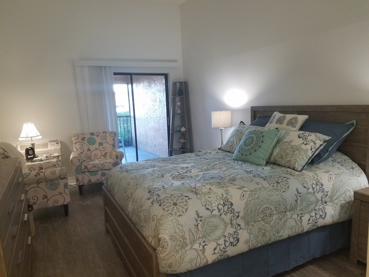 A cozy bedroom with a patterned bedspread, decorative pillows, and matching chairs.