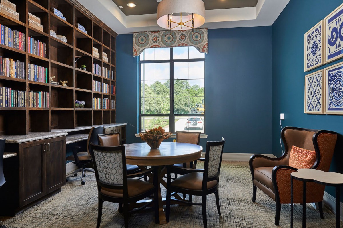 A stylish office interior with a round table, chairs, and a large bookshelf against blue walls.