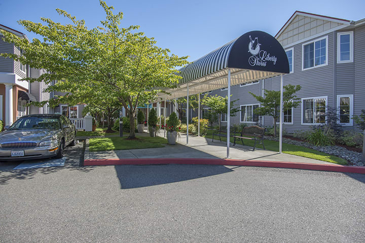 A building entrance with an awning and a landscaped driveway.