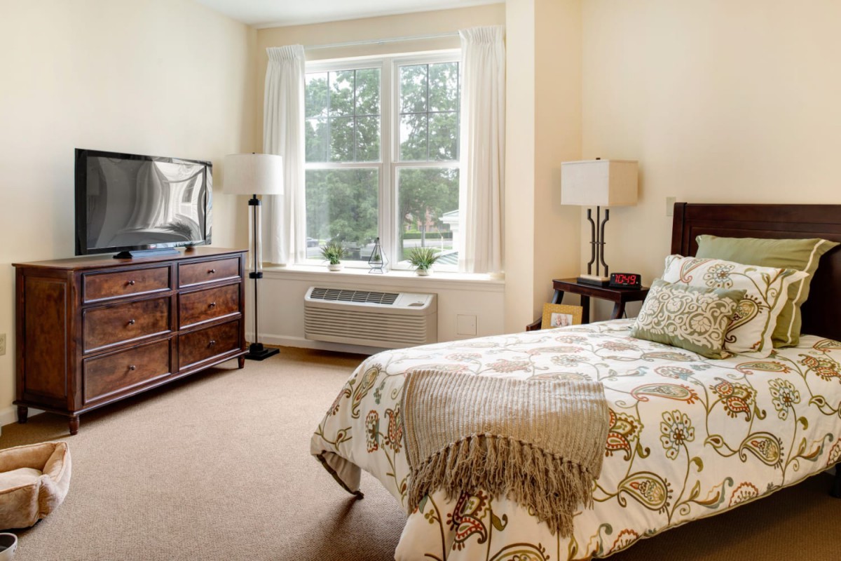 A cozy bedroom with a single bed, large window, and elegant furnishings.