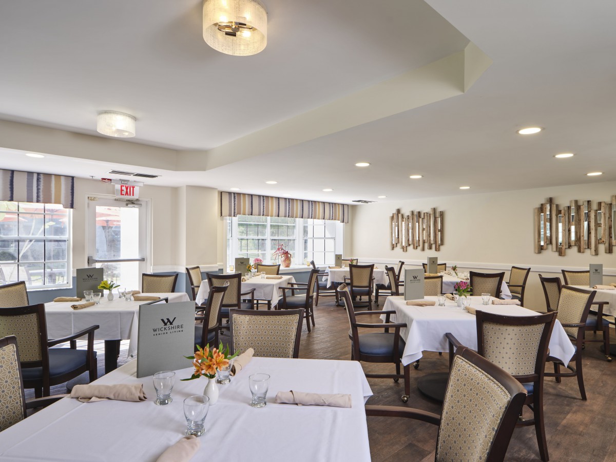 A bright and neatly arranged dining room with multiple tables set for guests.