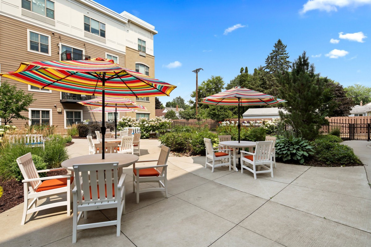 A sunny patio with colorful umbrellas and outdoor seating in a garden setting.