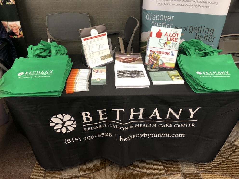 A promotional table for Bethany Rehabilitation & Health Care Center featuring informational brochures and branded tote bags.