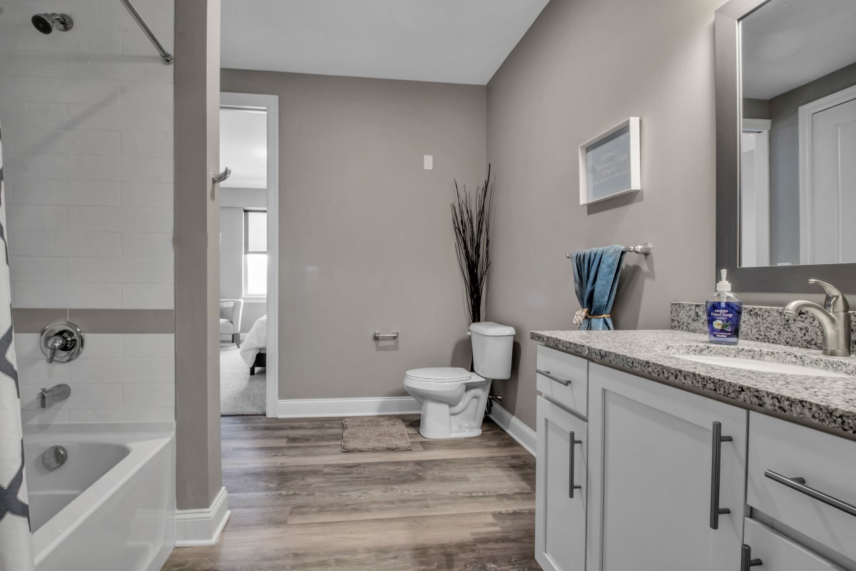 A modern bathroom with neutral tones, featuring a toilet, sink, mirror, and elegant decor.