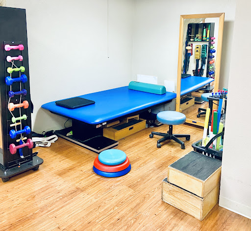 A well-equipped physiotherapy room featuring various exercise tools and a treatment table.