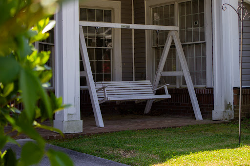 A charming white swing on a porch, inviting relaxation in a cozy outdoor space.