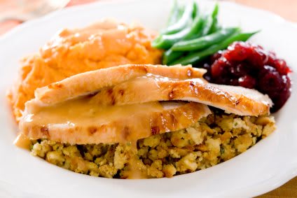 A plate featuring turkey slices, stuffing, mashed potatoes, green beans, and cranberry sauce.