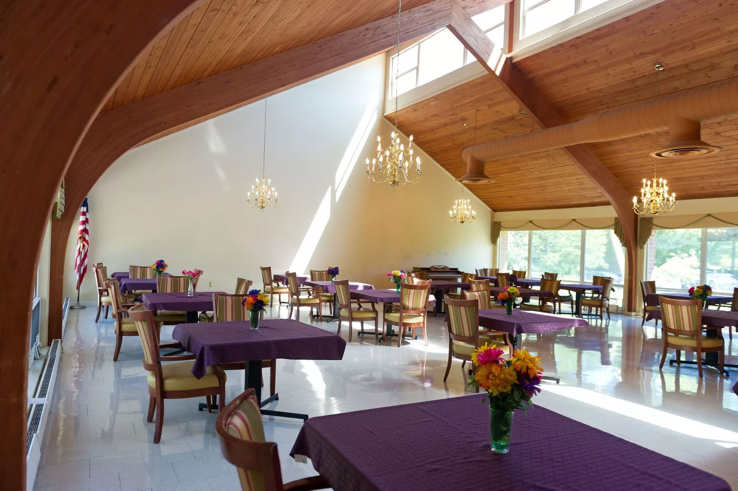 A bright and airy restaurant dining area with purple tablecloths and floral centerpieces.