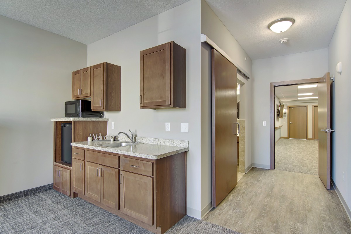 A small kitchen area with wooden cabinets, a sink, and a microwave.