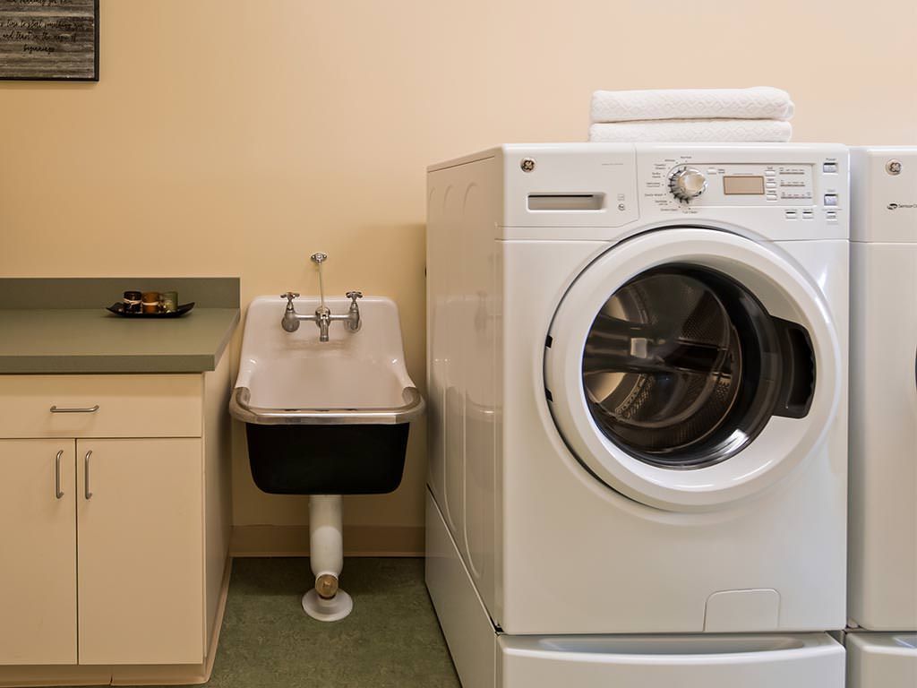 Laundry room with a washing machine and a utility sink.