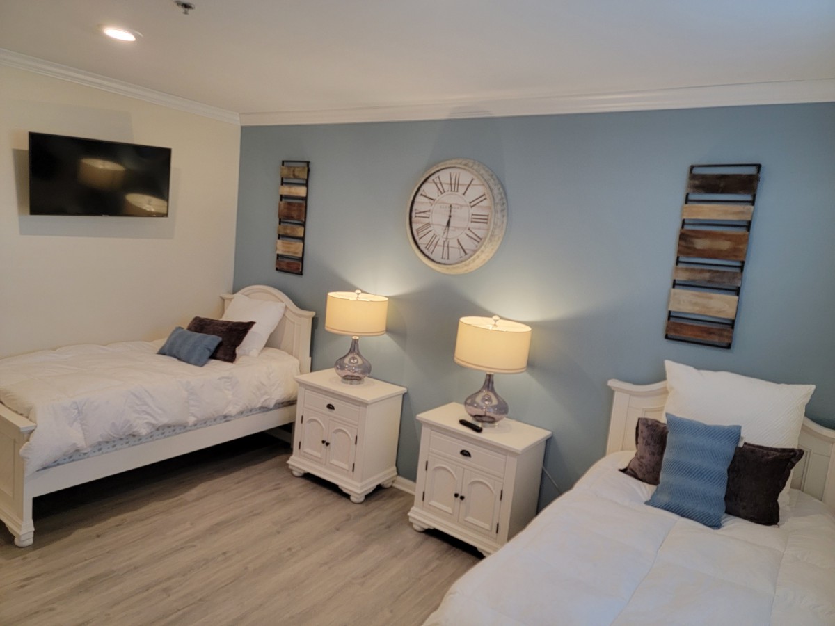 A cozy bedroom with twin beds, nightstands, and decorative elements against a blue accent wall.