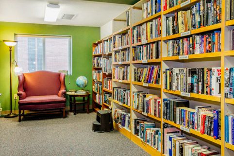 A cozy library corner with bookshelves, a globe, and a comfortable chair.