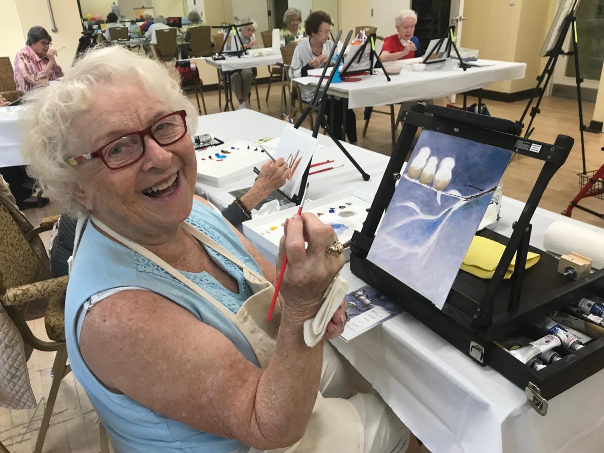 A joyful woman painting in an art class, enjoying her creative hobby.