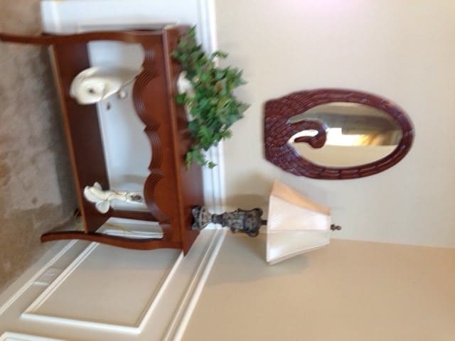A room with a decorative shelf, an ornate mirror, and a lamp.