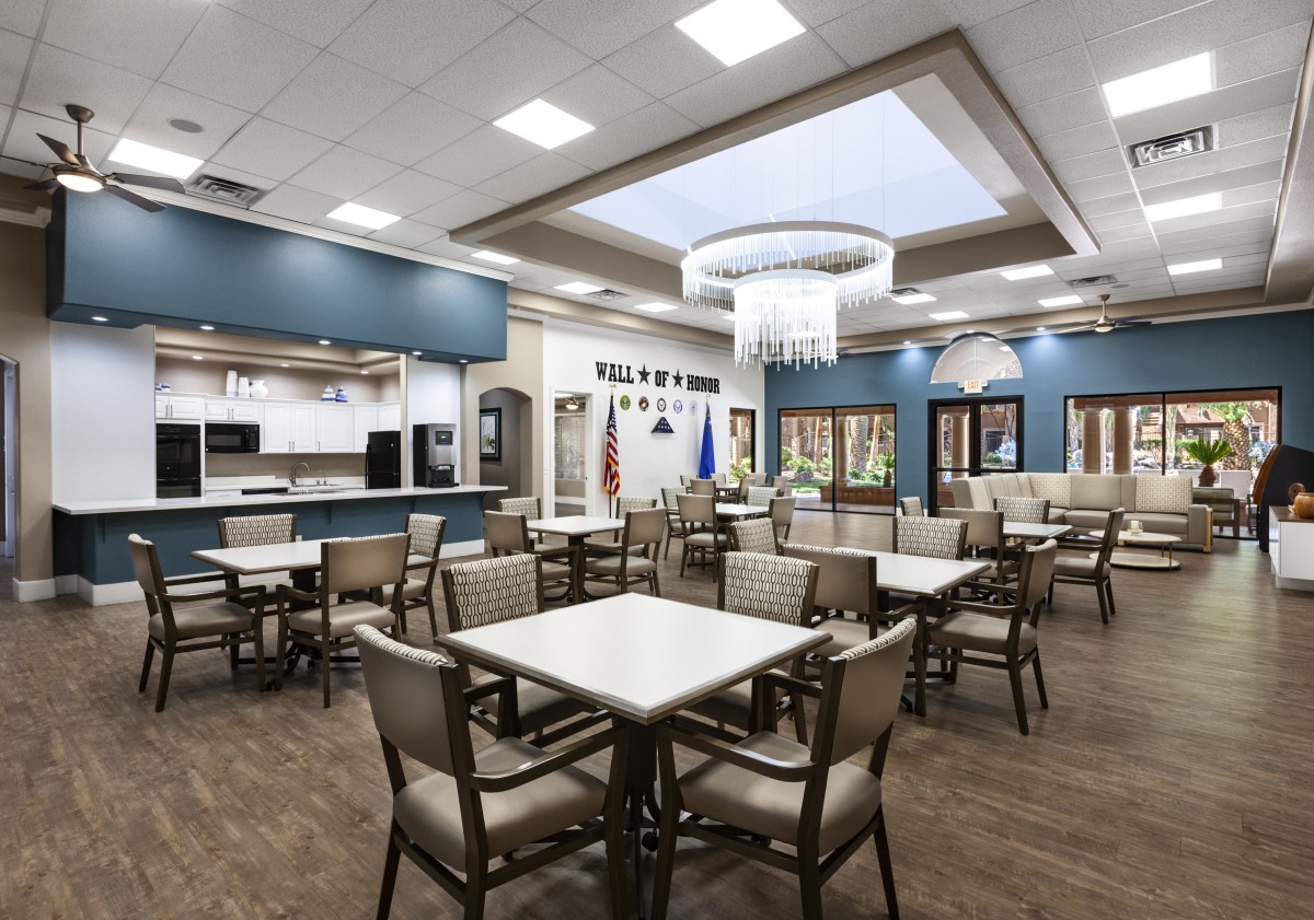 A spacious and modern dining area with tables and chairs, featuring a large chandelier and ceiling lights.