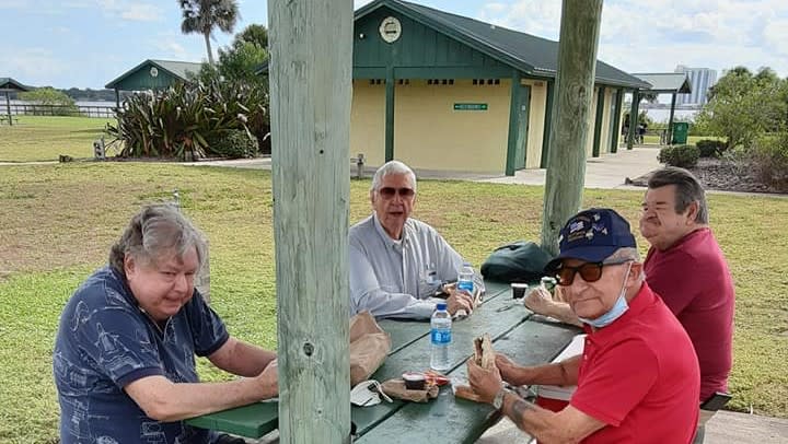 A group of people enjoying a picnic at a park table.