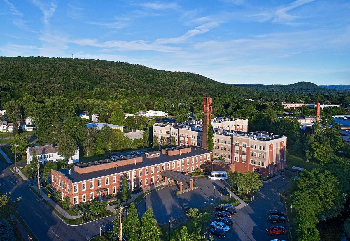 Aerial view of a hospital surrounded by trees and mountains.