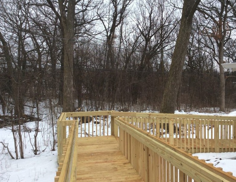 A wooden walkway in a snowy forest landscape.