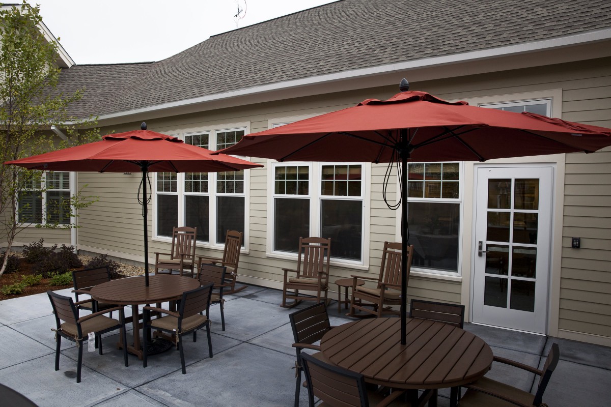 Outdoor patio area with tables, chairs, and red umbrellas.
