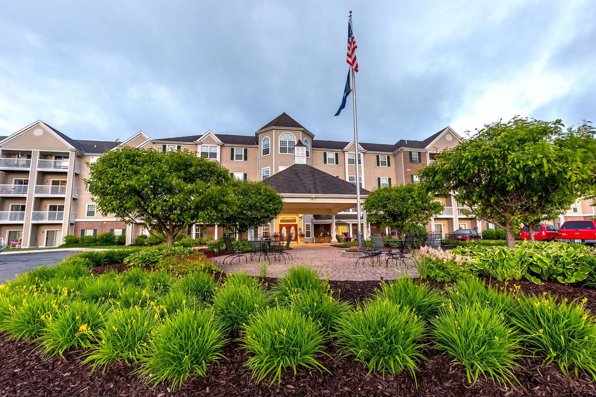Front view of a hotel with landscaped gardens and an American flag.