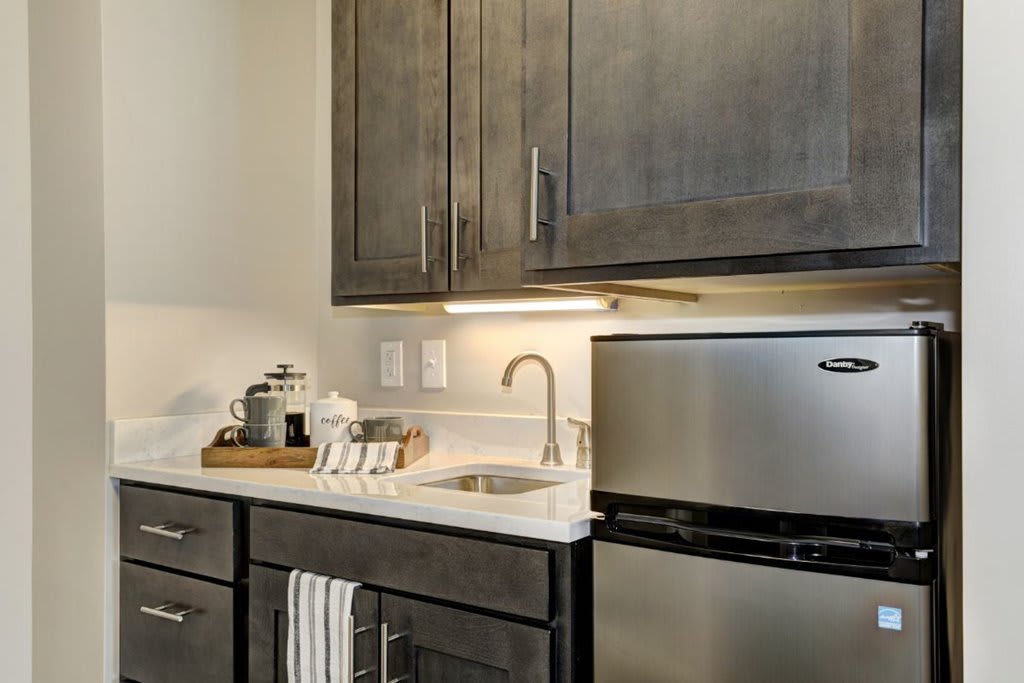 A modern kitchen with dark cabinets and stainless steel appliances.