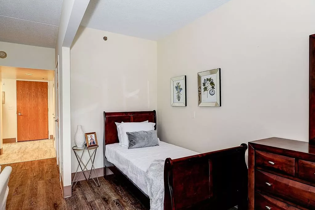 A cozy bedroom with a single bed, wooden furniture, and elegant wall decor.