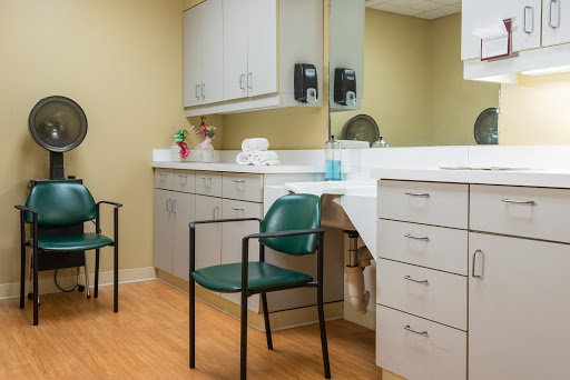 A clean and organized medical waiting room with green chairs and a reception counter.