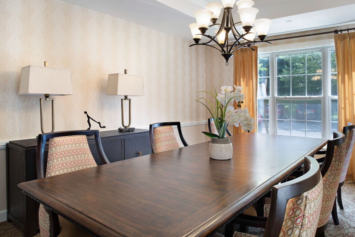 Elegant dining room with a large wooden table, chairs, and a chandelier.