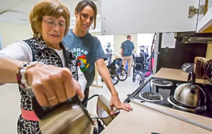 An elderly person receives assistance in the kitchen, emphasizing learning and support.