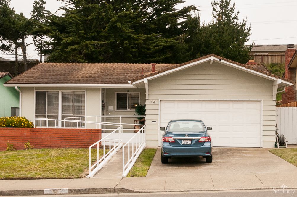 A suburban house with a car parked in the driveway next to a garage.