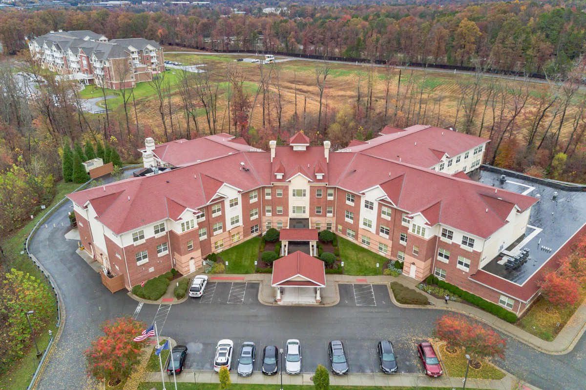 Aerial view of a residential building with a parking lot and autumn foliage.