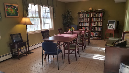 A cozy dining area featuring a wooden table surrounded by various chairs, illuminated by natural light from the windows.
