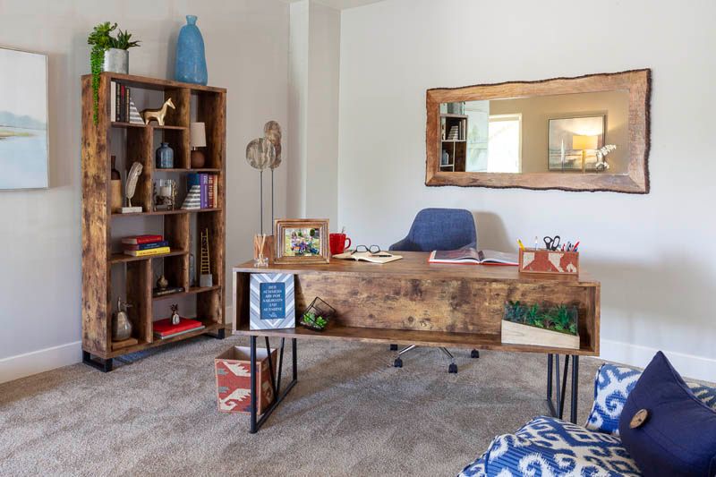 A cozy home office featuring a wooden desk and bookshelf with modern decor.