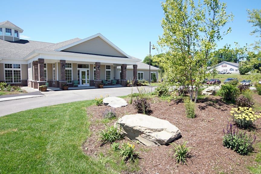 A well-maintained building with landscaped gardens featuring rocks, trees, and grass.