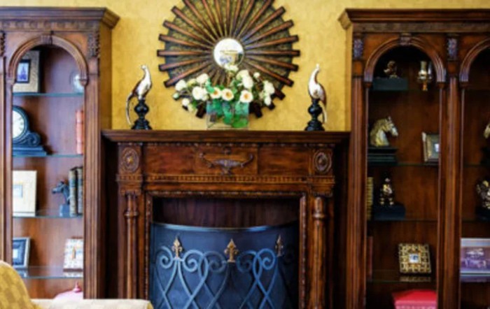 A beautifully decorated fireplace with a vintage wooden mantel, adorned with a decorative mirror and floral arrangement.