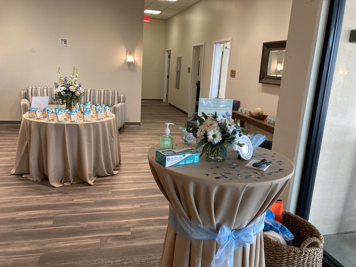 A decorated reception area with tables arranged for an event, adorned with flowers and elegant table settings.