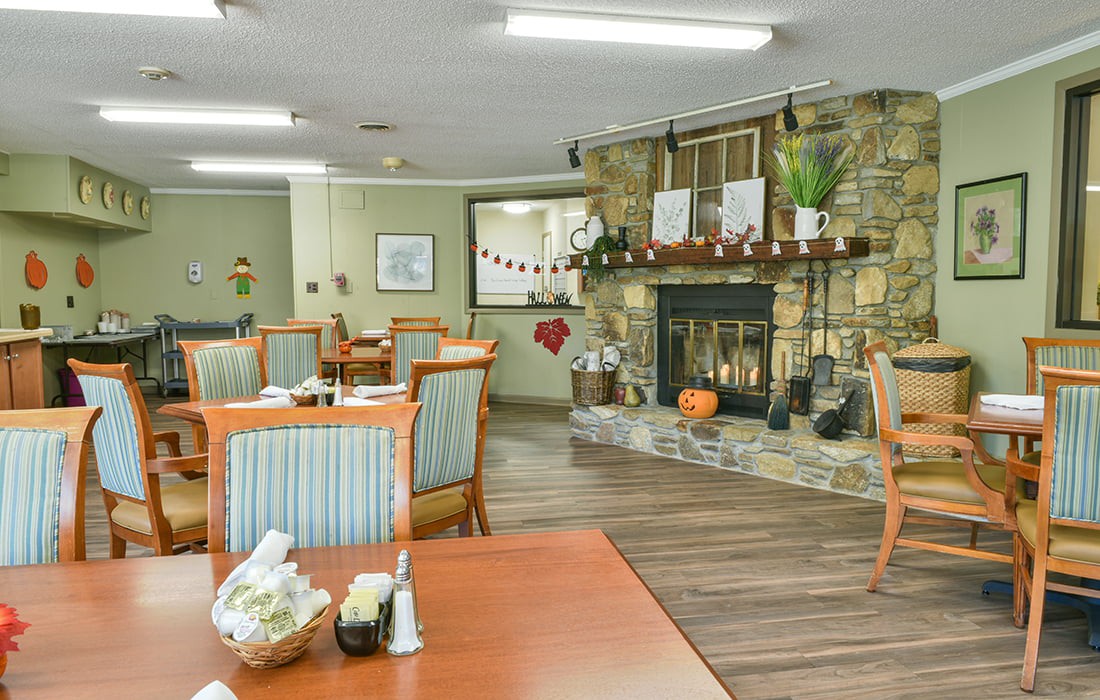 A cozy dining area with tables and chairs, featuring a decorative fireplace.