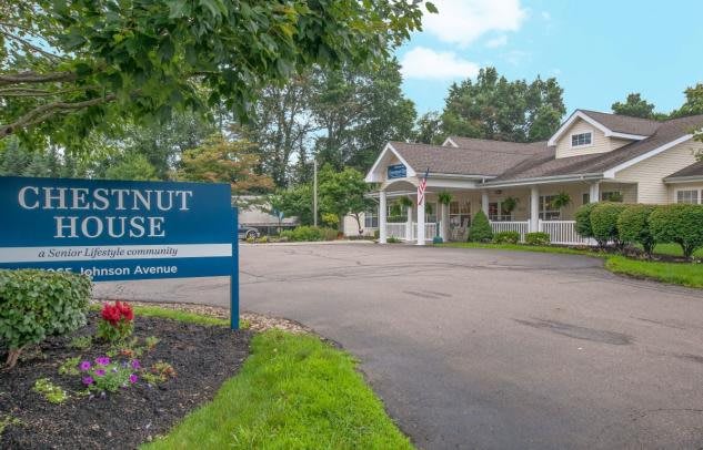 A building with a 'Walnut House' sign at the entrance, surrounded by trees and a clear sky.