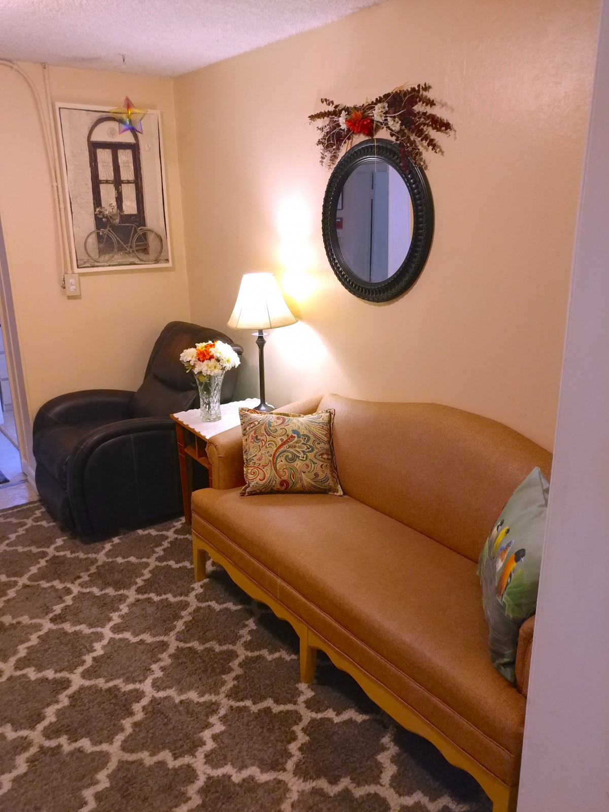 A cozy living room with warm lighting, featuring a sofa, armchair, and decorative elements.