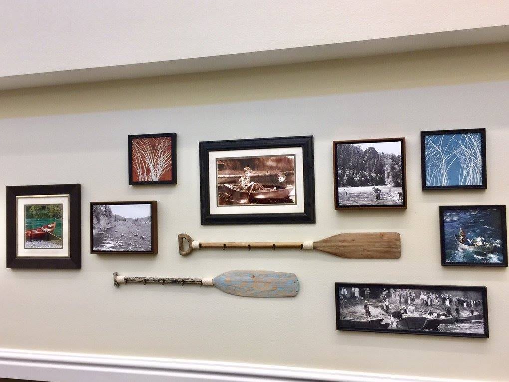 A gallery wall featuring a collection of black and white photographs and two decorative paddles.